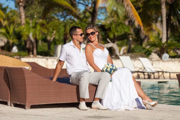 Young wedding couple sitting on the sunbed — Stockfoto