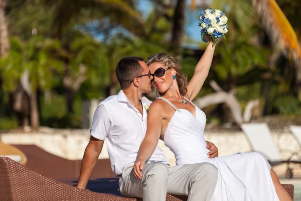 Young wedding couple sitting on the sunbed — Stock Photo, Image