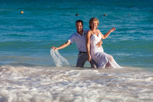 Junges Hochzeitspaar vergnügt sich in Meereswellen — Stockfoto