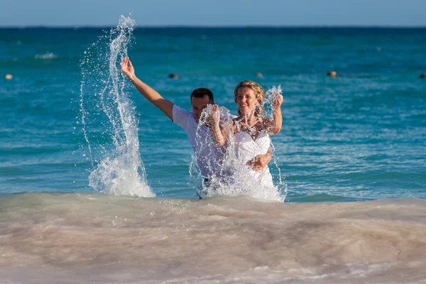 Young wedding couple have a fun in ocean waves — Stockfoto