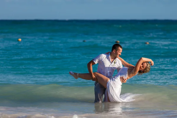 Junges Hochzeitspaar vergnügt sich in Meereswellen — Stockfoto