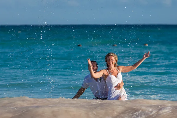 Young wedding couple have a fun in ocean waves — Stockfoto