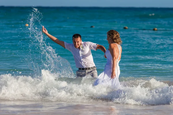 Casal jovem tem uma diversão em ondas do oceano — Fotografia de Stock