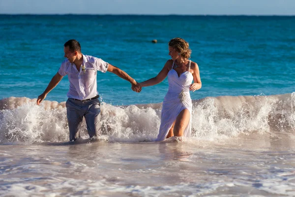Молода весільна пара розважається в океанічних хвилях — стокове фото