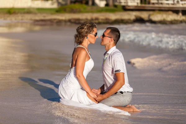 Ungt par sitter tillsammans på en sand av ocean — Stockfoto