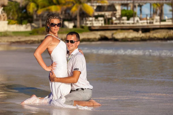 Ungt par sitter tillsammans på en sand av ocean — Stockfoto