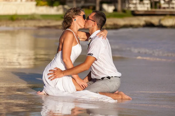 Young couple sitting together on a sand by ocean — Stock Photo, Image