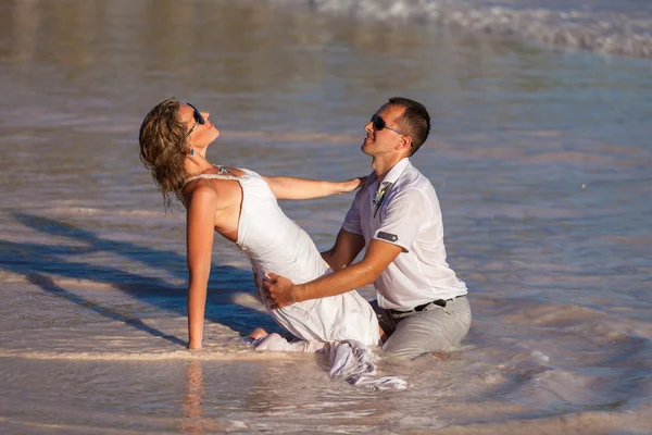 Ungt par sitter tillsammans på en sand av ocean — Stockfoto