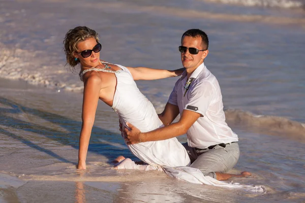 Young couple sitting together on a sand by ocean — Stock Photo, Image