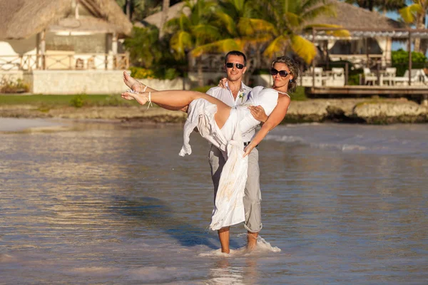 Guy holds girl on hands. Ocean beach — Stock Photo, Image