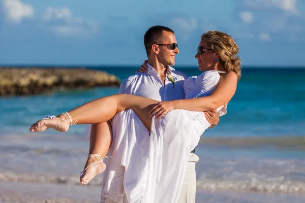 Le gars tient la fille sur les mains. Plage océanique Photos De Stock Libres De Droits