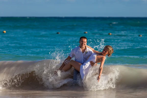 Joven pareja de boda se divierten en olas del océano Imagen de archivo