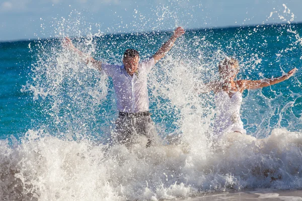 Joven pareja de boda se divierten en olas del océano Fotos de stock libres de derechos