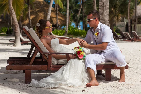 Marido y mujer relajándose en tumbonas en la playa — Foto de Stock