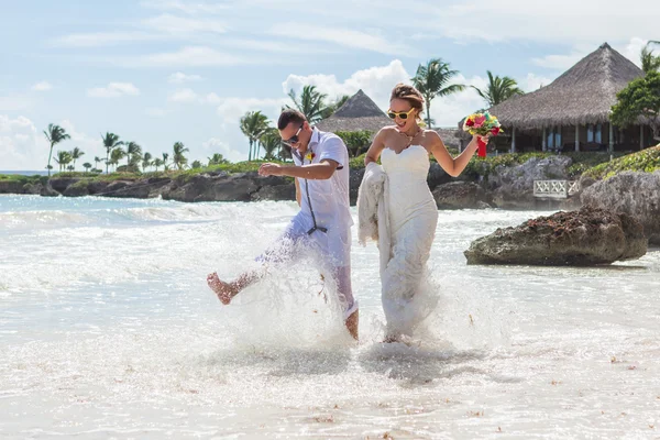 Par som springer genom vågor på stranden semester — Stockfoto