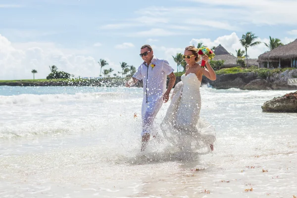 Casal correndo através de ondas em férias na praia — Fotografia de Stock