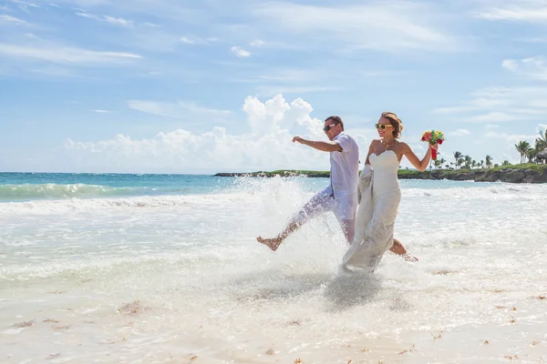 Casal correndo através de ondas em férias na praia — Fotografia de Stock