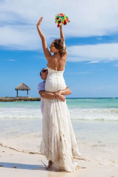 El tipo tiene a la chica en las manos. Playa del océano Imagen de stock