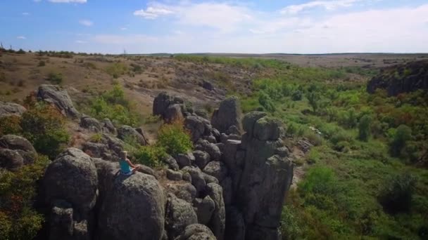 Antenne: Frau sitzt in Lotusposition auf Felsen — Stockvideo