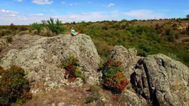 Anteni: lotus pozisyonu kayaya oturan kadın