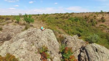 Anteni: lotus pozisyonu kayaya oturan kadın