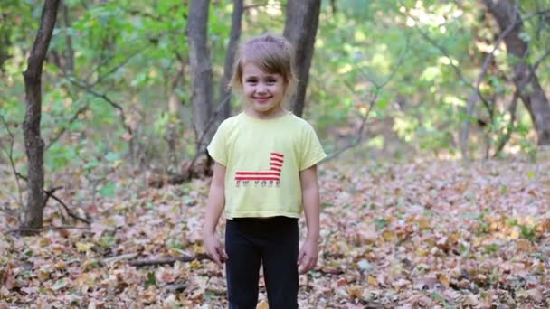 Petite fille sous les feuilles d'automne tombant — Video