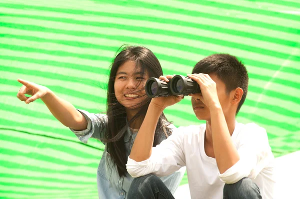 Asian młody chłopak i dziewczyna siedzieć szuka lornetki . — Zdjęcie stockowe