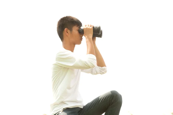 Asiatique jeune garçon assis est à la recherche de jumelles  . — Photo