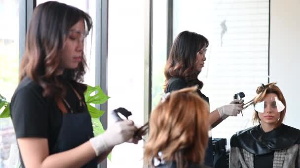 アジアの女性の美容師は美しい外国人顧客を削減します 近代的な理容室で バンコクのダウンタウンエリア — ストック動画