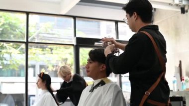Asyalı erkek kuaför, Bangkok 'taki modern güzellik salonlarında Asyalı erkek müşteriler için saç stili yapıyor..