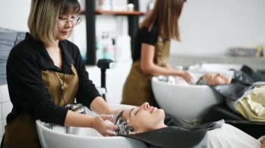 Kuaför kuaförde bir kuaför kuaförde bir müşteri için saç yıkar ve kadınlar bir sandalyede uzanıp saçlarını ve kafa derisini profesyonelce yüzer..