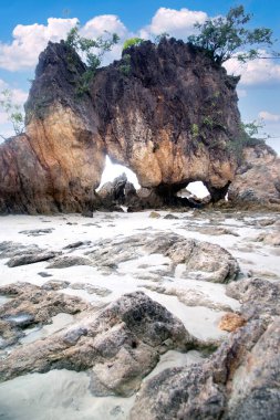 Delikleri ve deniz manzaralı kayalık bir sahil. Kumlu sahilde kayalık kayalıklar ve okyanus dalgaları.