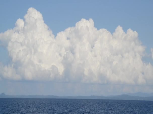 在强烈的阳光下 白色蓬松的云彩飘浮在深蓝色的海面上 — 图库视频影像