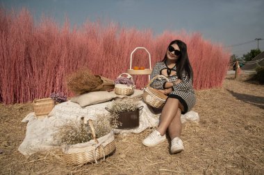 Güzel bir Asyalı şişman kadın, halk parkında arka planda pembe kuru ağaçlarla poz veriyor.. 