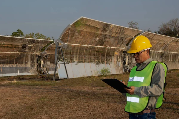 Staff in uniforms and helmets are checking and recording in the journal of the parabolic solar rail.