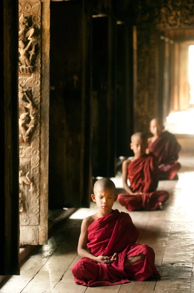 Tre unge munke sidder på Shwenandaw Kloster i Mandalay, Myanmar . - Stock-foto