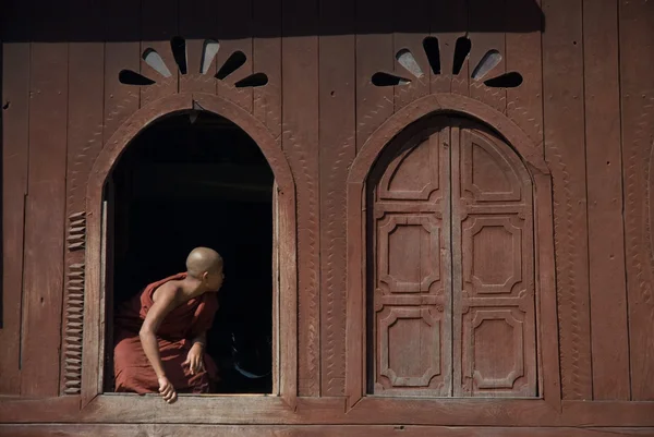 Молодой монах на окне в храме Нян Шве-Кгуа, озеро Инле в Мьянме . — стоковое фото