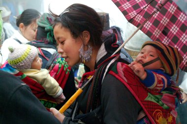 Çocuk taşıyan ve geleneksel kıyafetleri giyen Hmong kadın.