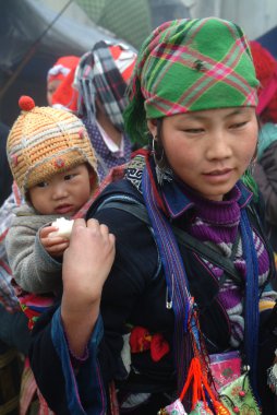 Çocuk taşıyan ve geleneksel kıyafetleri giyen Hmong kadın.