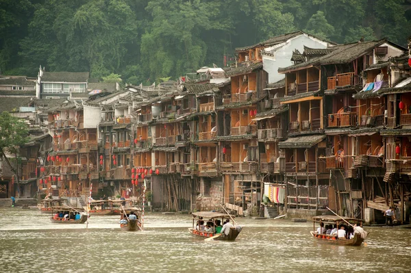 Turistit rentoutua, ottaa veneretki joen Fenghuang ancie — kuvapankkivalokuva