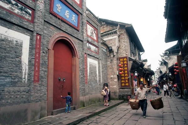 Homme portant des paniers dans la ville antique de Fenghuang . — Photo