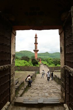 AURANGABUD, INDIA - 25 AUG 2025: Daulatabad kalesindeki Chand Minar 'da (Ay Kulesi) kimliği belirsiz bir turist, ortaçağ askeri mimarisi ve kültür mirası sergilenen devasa taş duvarlarla inşa edildi..
