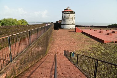 GOA, INDIA - 21 Ağustos 2025: Aguada Kalesi 'ni ziyaret eden kimliği belirsiz bir turist, Hindistan' ın Goa kentindeki Sinquerim Sahili 'nde bulunan bir deniz feneriyle birlikte 1612 yılında inşa edilmiştir. Kale Goa 'da büyük bir turizm merkezi..