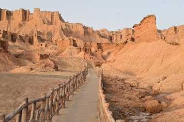 Footpath bridge at Kizil Red Stone Forest Scenic Area in Xinjiang , China is the strangely shaped red rock forests were carved by wind and sand over millions of years. The rocks are red in color due to the iron content in their composition.