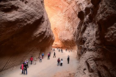 XINJIANG, ÇİN - OCT 24, 2025: Tianshan Büyük Kanyonu 'nda yürüyen tanımlanamayan turistler, veya Kesileya Büyük Kanyonu, milyonlarca yıllık rüzgar ve yağmur erozyonunun oluşturduğu kendine özgü kırmızı kanyonlarıyla karakterize edilen çarpıcı bir doğal özelliktir.. 