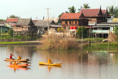 Buddhist monks are given food offering from people by boat.