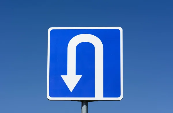 Синій дорожній знак з дорожнім знаком U Turn з фоном блакитного неба — стокове фото