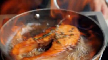 Somon, şef tarafından tavada kızartılır. Restoran yemeği. Balık kızartırken tavadan çıkan ateş. Gastronomik gösteri. Balık fileto mutfağı lezzetleri