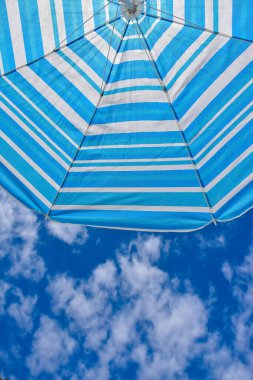 Menorca adasında bulutlar ve plaj şemsiyesiyle mavi gökyüzü arka planı