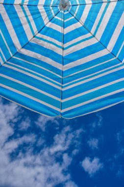 Menorca adasında bulutlar ve plaj şemsiyesiyle mavi gökyüzü arka planı